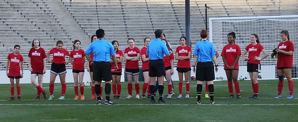 Players in red jerseys lined up with referees before the exhibition match