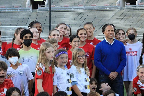 Cobi Jones in a blue sweater posing with a group of Region 13 girls