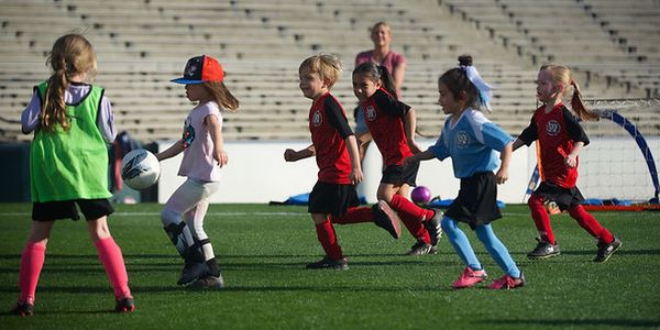 Small girls in red and green pinnies playing a small-sided game inside the Rose Bowl