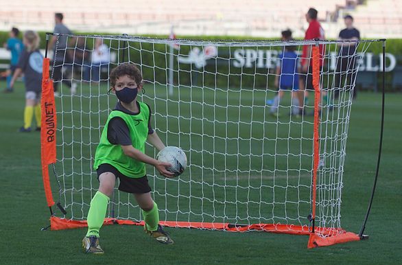 Boy in a green pinnie playing in goal during a small-sided game at Spieker Field