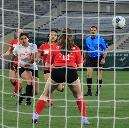 Players in Celebration and Sisterhood jerseys near the goal as the ball flies in