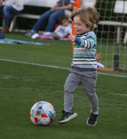 Toddler chasing a soccer ball across the grass